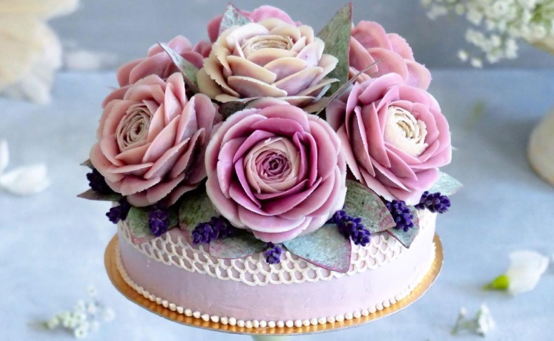 Feminino mão decorando o bolo de aniversário de casamento flor rosa no  carrinho.